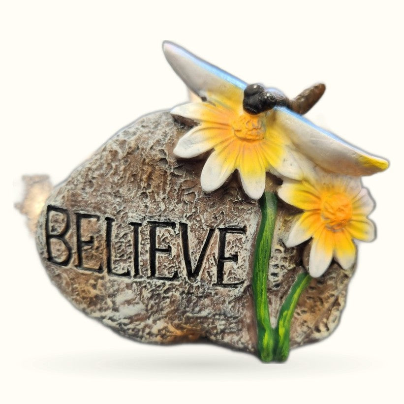 Stone garden rock ornament with 'BELIEVE' text, decorative bee, and yellow and white daisy flowers