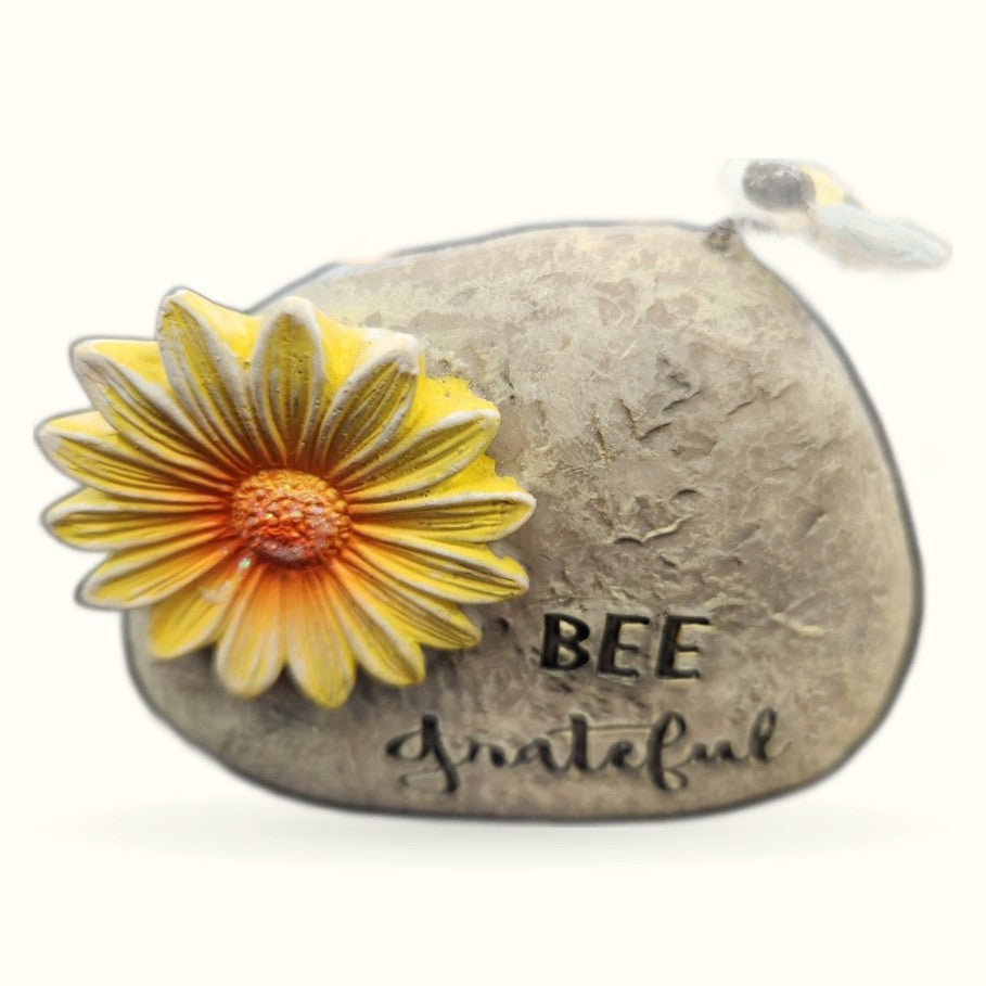 Gray stone garden rock with 'BEE grateful' text and yellow daisy flower with bee illustration on top
