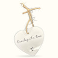 White heart-shaped plaque with 'One day at a time' text, hung from twine and driftwood on white background