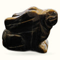 Polished tiger's eye stone carved into a rabbit figurine with golden and black striations