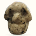 Polished moonstone skull carving with natural dark inclusions and warm beige coloring