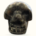 Polished black moonstone skull carving with smooth finish and visible grey striations
