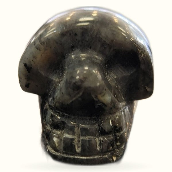 Polished black moonstone skull carving with smooth finish and visible grey striations
