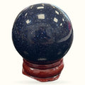 Blue Goldstone sphere 4cm with glittering dark blue surface on wooden stand