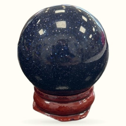 Blue Goldstone sphere 4cm with glittering dark blue surface on wooden stand