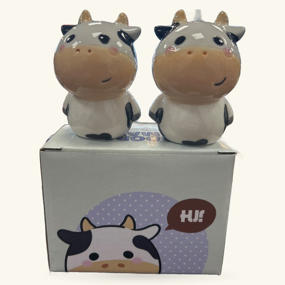 Two ceramic cow salt and pepper shakers with black and white coloring, smiling faces, displayed with product box