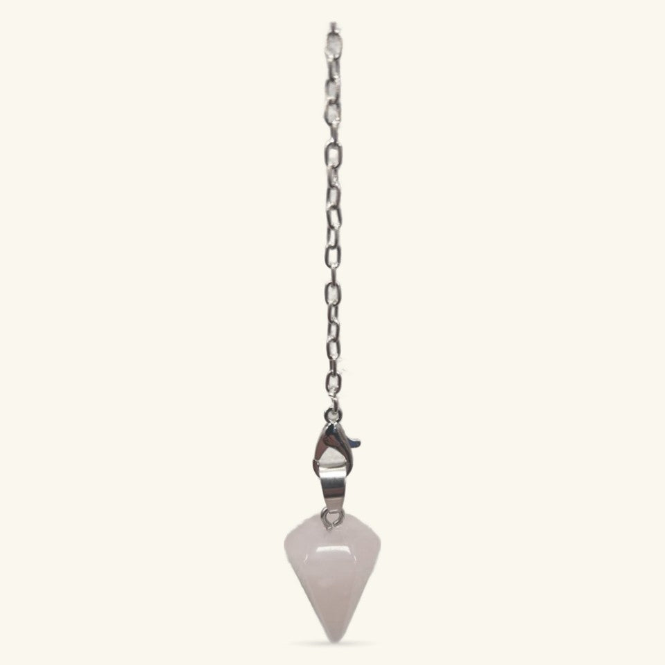 Rose quartz point pendulum with metal clasp hanging from silver chain on cream background