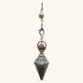 Tigers Eye crystal pendulum with ornate silver metalwork cap and filigree details, hanging from delicate chain