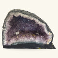 Large amethyst geode cave with deep purple crystals and pale lavender outer band, dark exterior