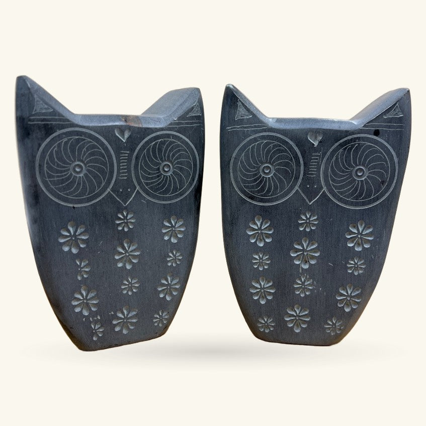 Pair of dark stone owl bookends with spiral eye details and embossed flower patterns on body