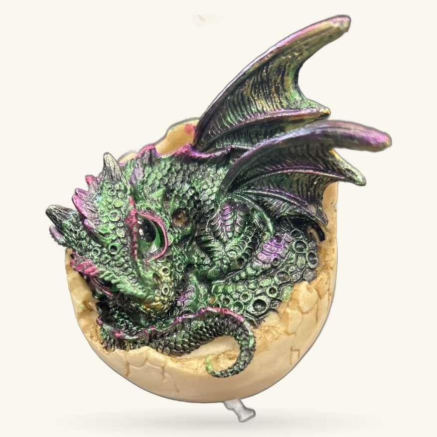 Green and purple metallic dragon hatching from cream-colored egg, detailed scales and fins visible