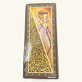 Slim tarot card deck with ornate gold filigree border and illustration of winged fairy figure in purple and pink robes