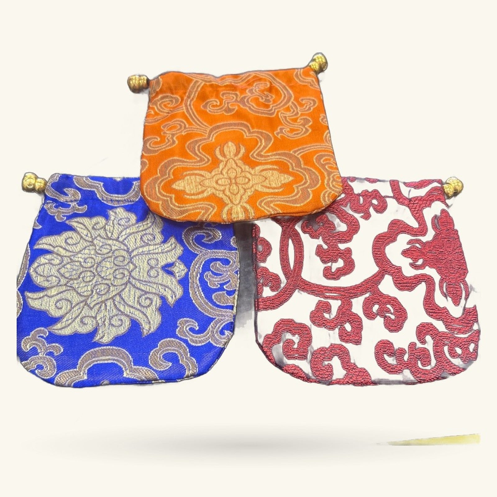 Three decorative Chinese embroidery fabric purses in orange, blue, and red with gold ornamental patterns and brass bead closures