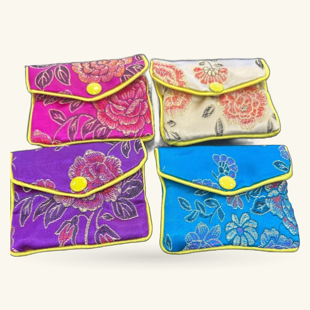 Four small embroidered purses in magenta, cream, purple, and blue with yellow trim and snap closures