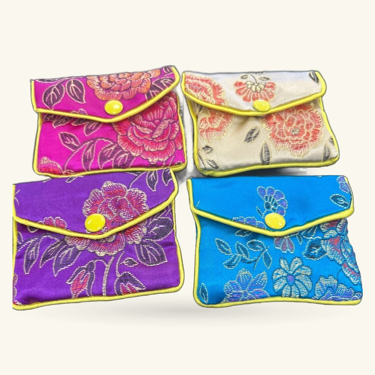 Four small embroidered purses in magenta, cream, purple, and blue with yellow trim and snap closures