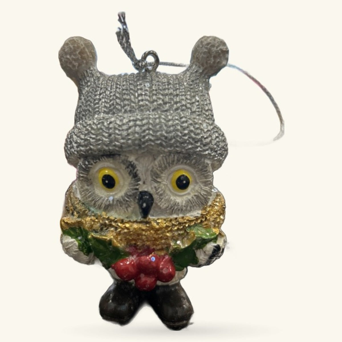 Grey knitted owl ornament with golden collar, red berries, green leaves, and mistletoe sprig