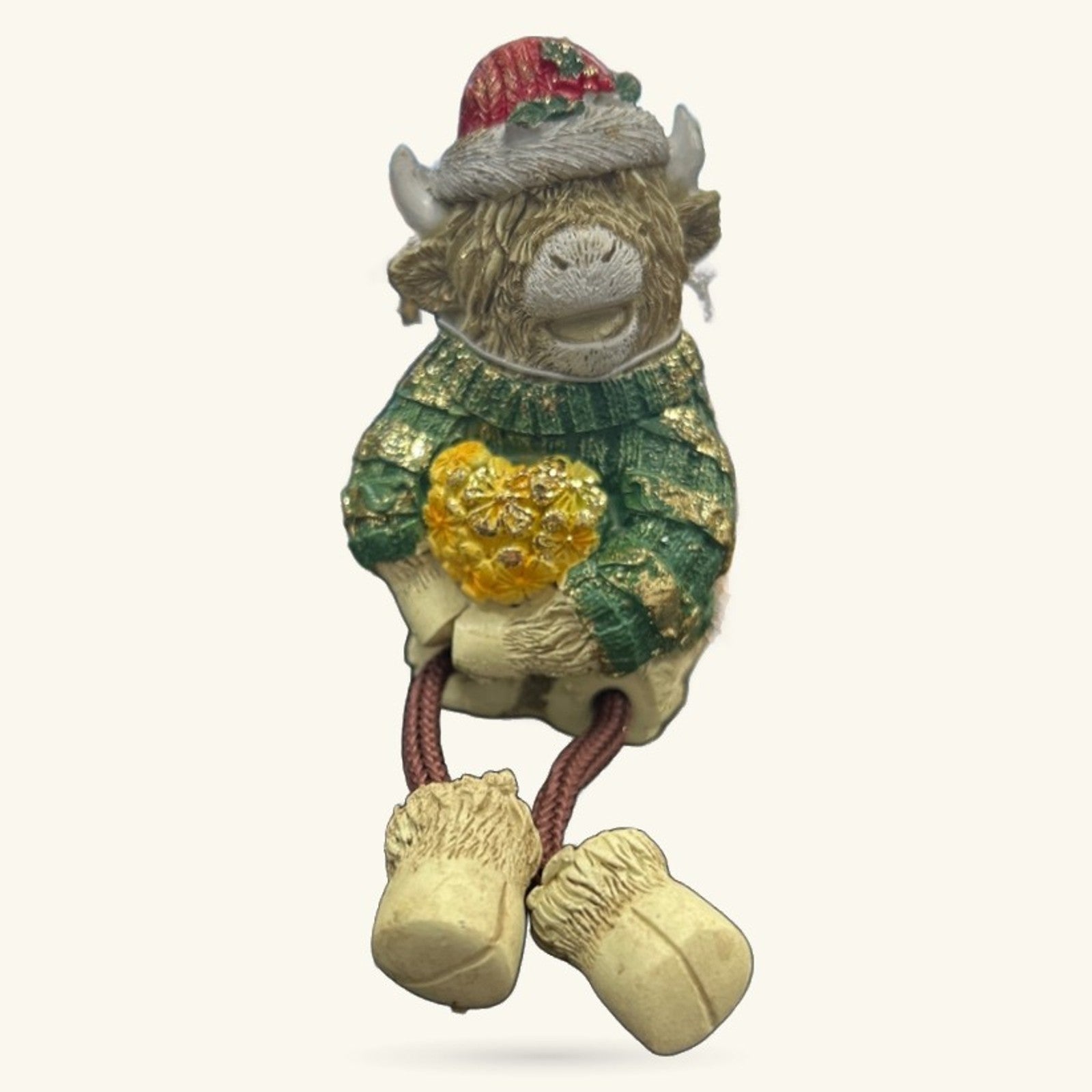 Cute ceramic Highland cow figurine wearing red Santa hat and green sweater with gold detail, dangly legs