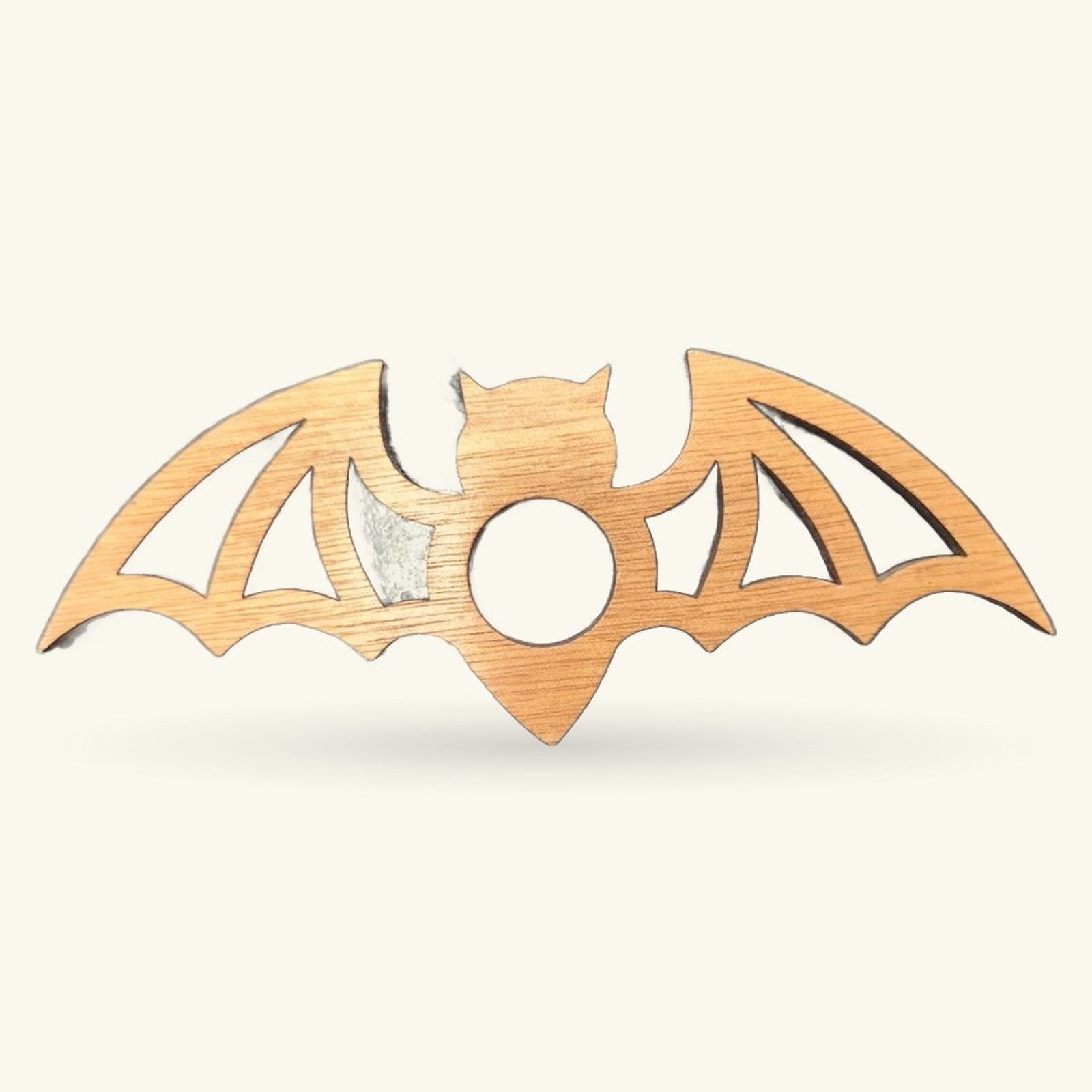 Wooden bat-shaped stand with carved wings, cat head, and circular center hole on cream background