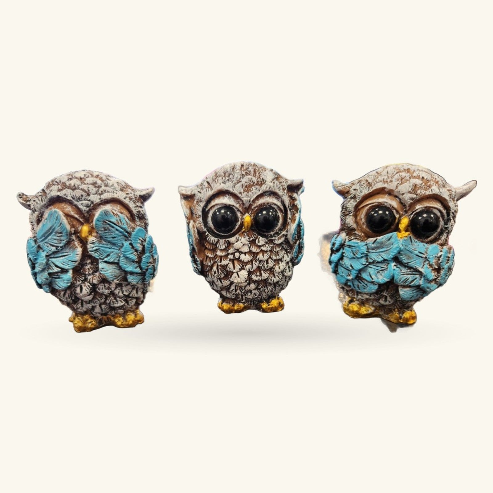 Three decorative owl figurines in see-hear-speak no evil poses with turquoise wings and gold feet