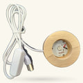 White power cord with plug connected to round natural wood light base with electronic control unit