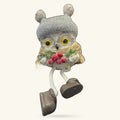 Gray knitted owl ornament with yellow eyes, red berries, gold wings, and dangling legs with black feet