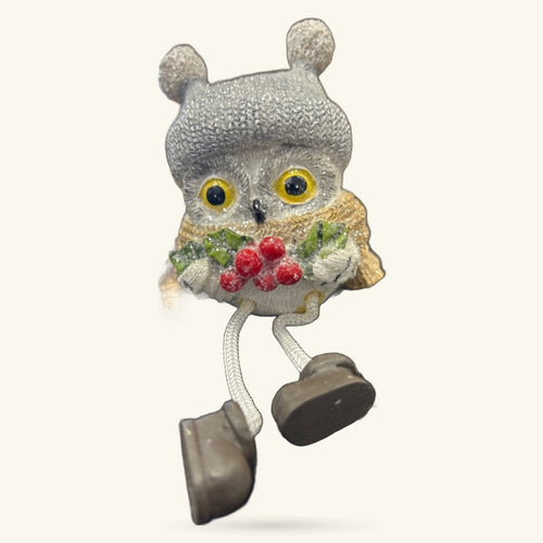 Gray knitted owl ornament with yellow eyes, red berries, gold wings, and dangling legs with black feet