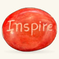 Red polished stone with 'Inspire' engraved on surface, oval shape, 3cm size