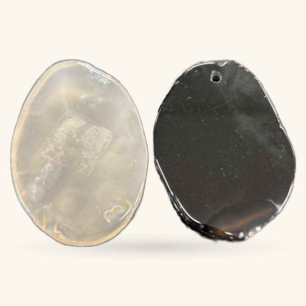 Two polished agate slice pendants shown front and back - one milky translucent, one dark charcoal with drilling hole