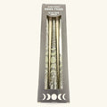 Set of three cream taper candles with silver moon phase designs in dark gray packaging box