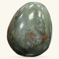 Polished bloodstone egg with red iron oxide inclusions on grey-green stone, smooth curved shape