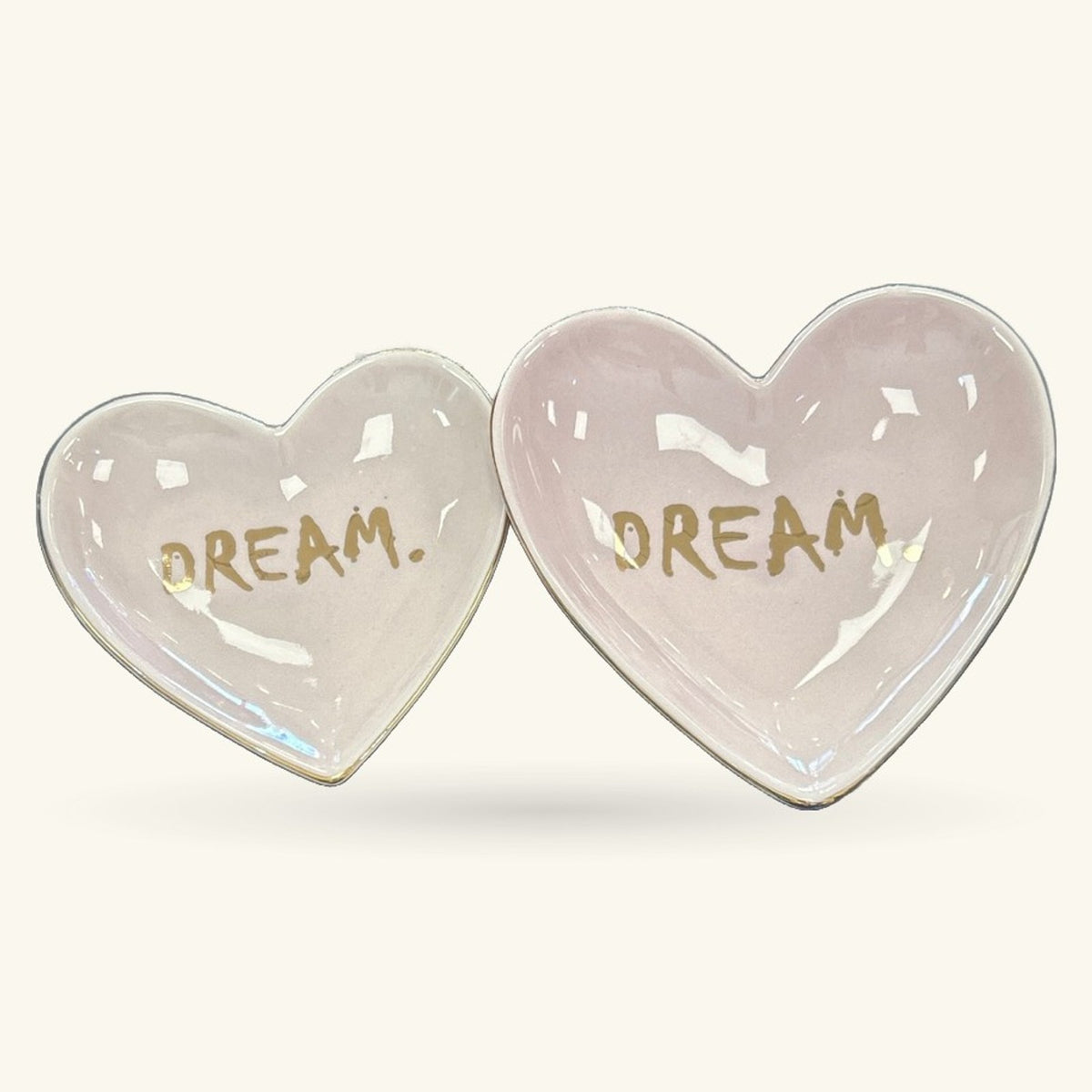 Two pale pink heart-shaped ceramic trinket trays with 'DREAM' written in gold script on each