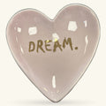 Heart-shaped pink ceramic trinket tray with gold 'DREAM.' text and white glazed accents