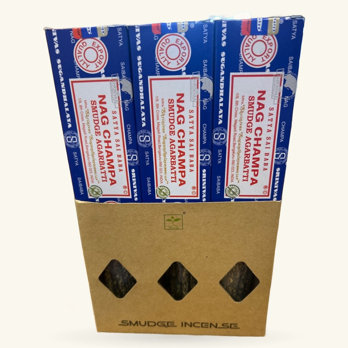 Three boxes of Satya Nag Champa Smudge Incense stacked in a kraft cardboard display box with three diamond-shaped windows