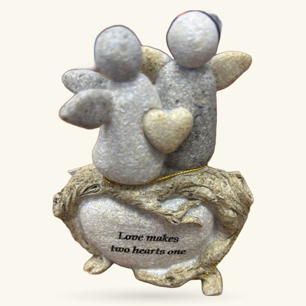 Two grey ceramic angel figures with wings and a golden heart, sitting on a carved stone base engraved with 'Love makes two hearts one'