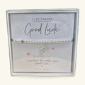 Silver beaded bracelet with star charm in a Life Charms gift box, 'Good Luck' card visible.
