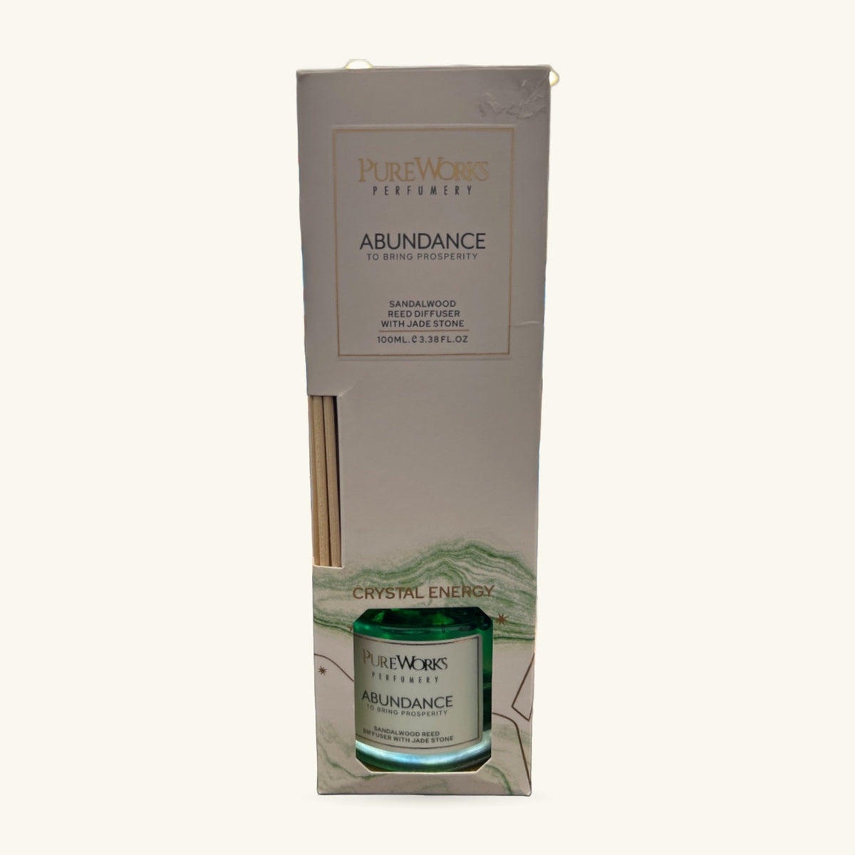 Pureworks Abundance reed diffuser in cream packaging, showing green glass bottle with reeds and jade stone detail