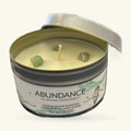 Tin candle with cream soy wax, single wick, and embedded jade stones, labeled Abundance Sandalwood scent.
