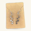 Silver moon and star drop earrings on kraft paper display card