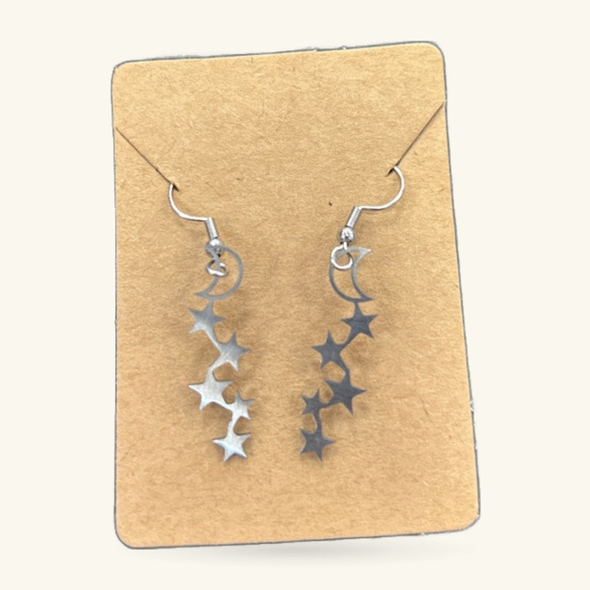 Silver moon and star drop earrings on kraft paper display card