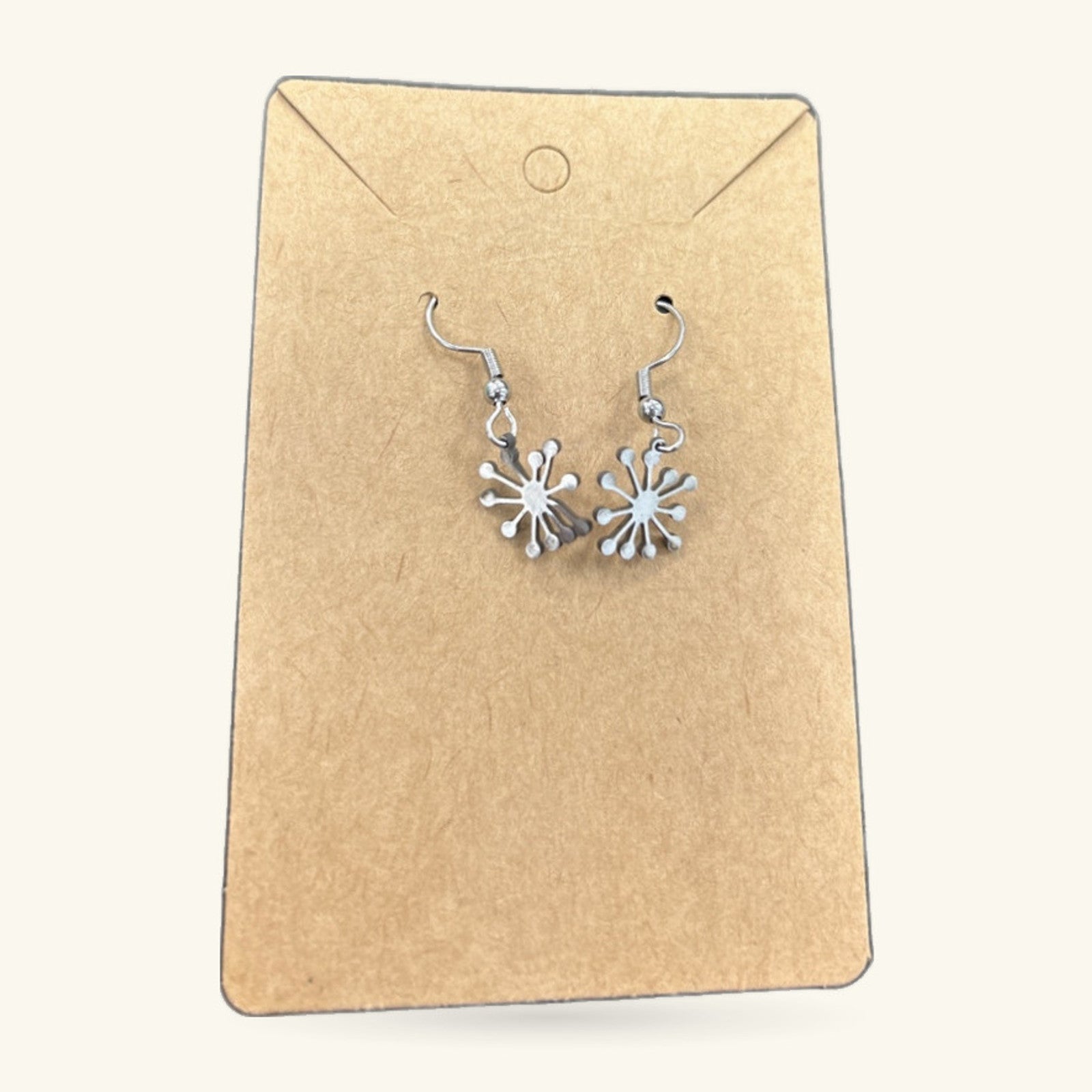 Pair of silver dandelion earrings on kraft paper display card with hook fasteners