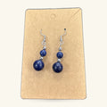 Pair of lapis lazuli bead earrings on kraft card display. Two-tier drop design with small and large round beads.