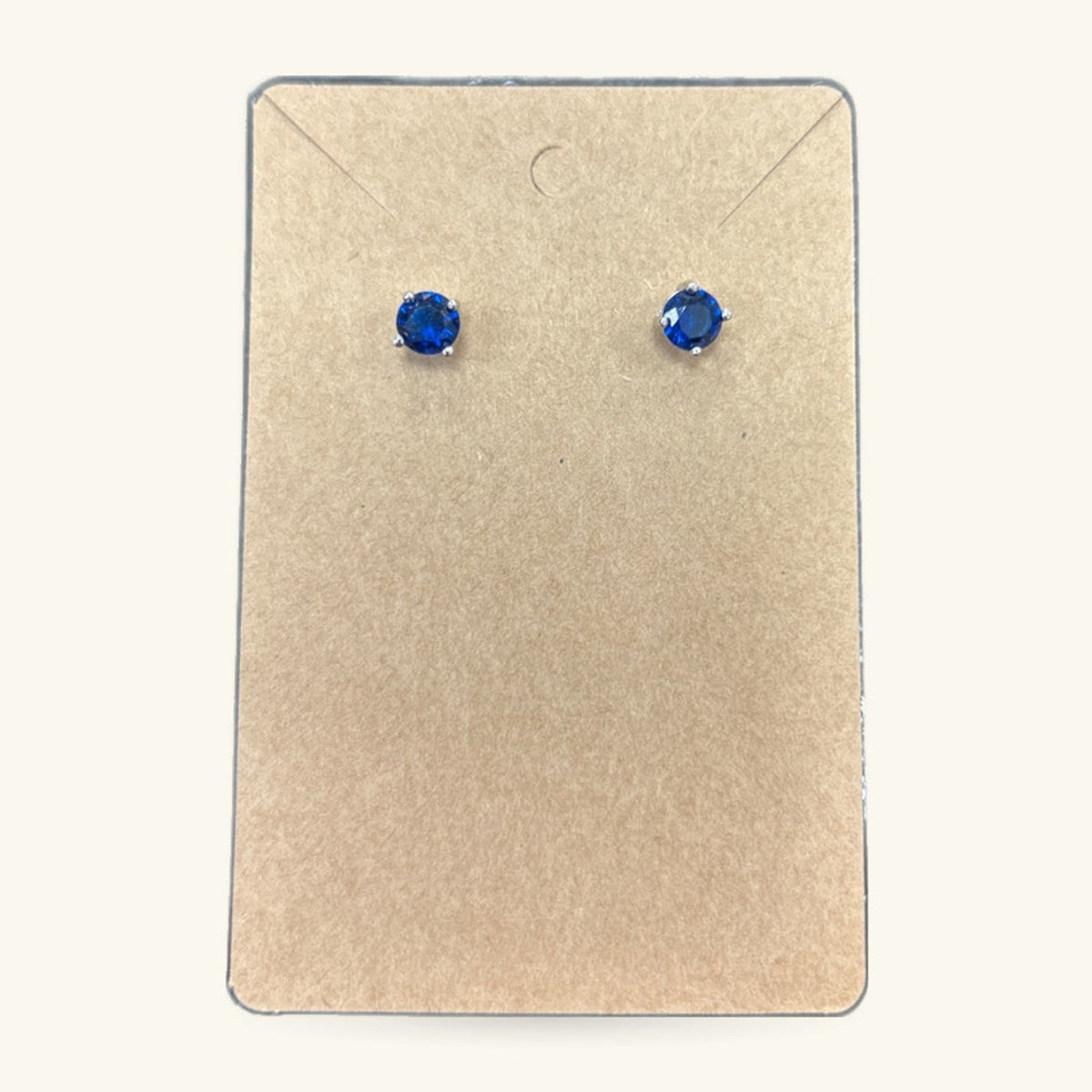 Pair of blue round stud earrings on a cream earring card with envelope flap
