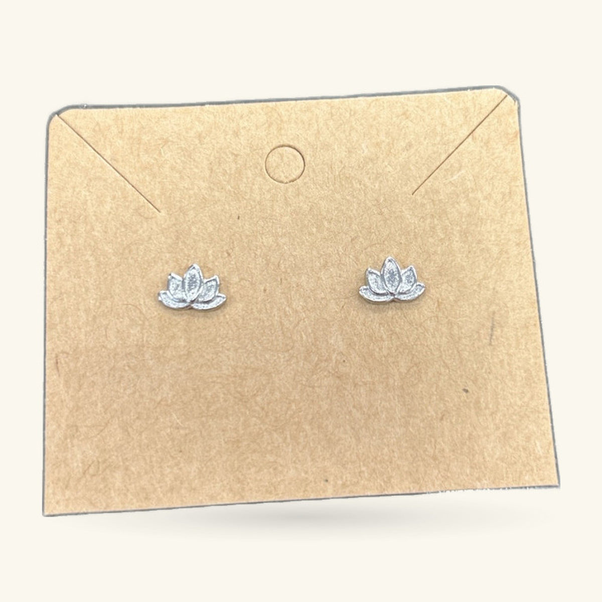 Pair of small silver lotus flower stud earrings on a kraft paper earring card