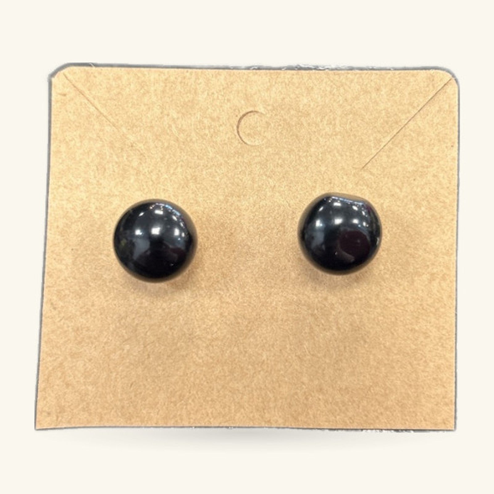 Pair of black glossy dome stud earrings on a kraft cardboard backing card