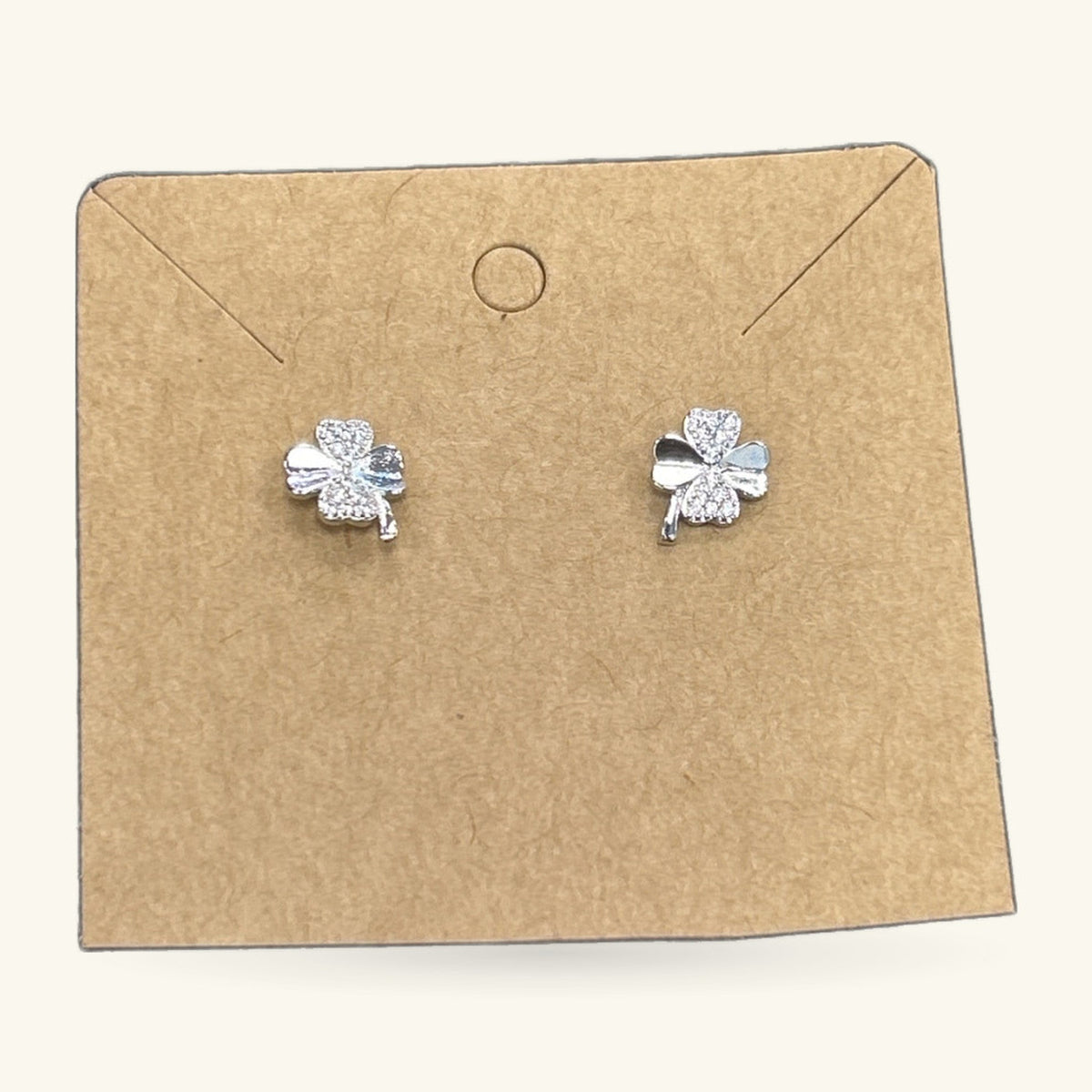 Pair of silver four leaf clover stud earrings on kraft earring card