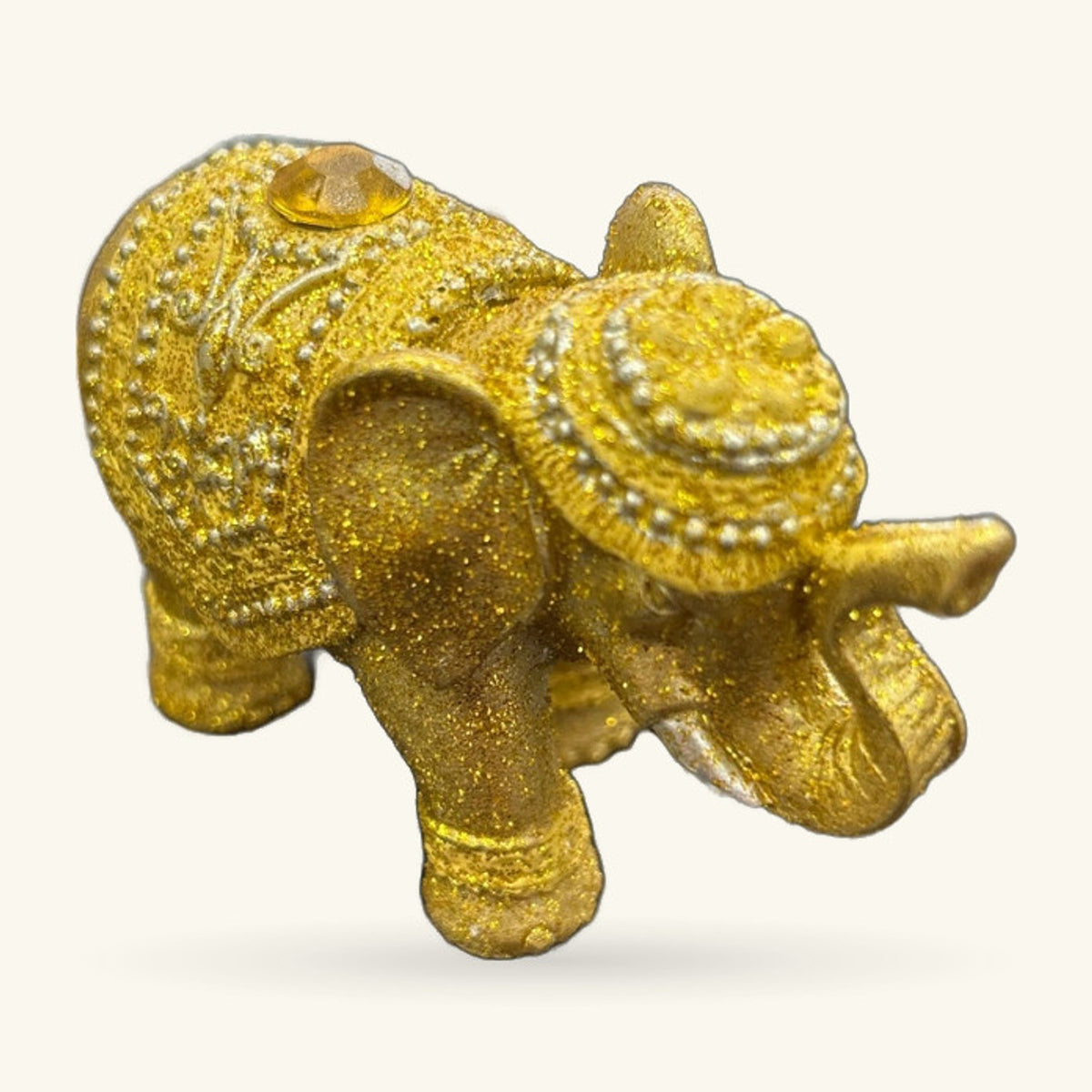 Gold glitter elephant figurine with beaded collar detail and yellow gem eye, side view