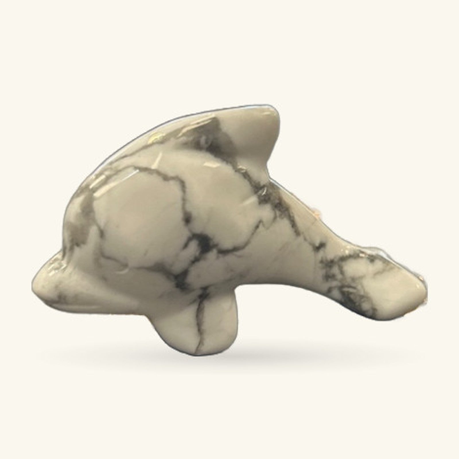 White Howlite carved dolphin figurine with natural dark veining, shown in profile