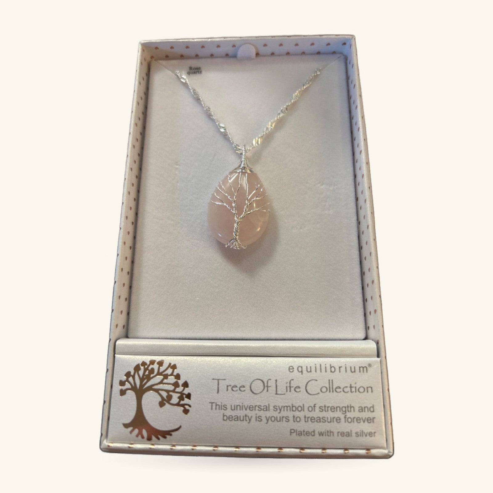 Rose quartz teardrop pendant with silver wire-wrapped tree of life design, hanging on silver chain in gift box