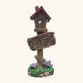 Wooden birdhouse ornament with burgundy roof on pole, 'Gnome Place Like Home' sign, moss base with purple flowers