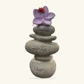 Stacked stone ornament with 'Home Sweet Home' text, topped with purple flower and red ladybug